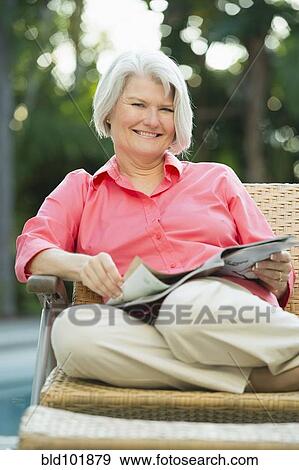 Stock Photo - Caucasian woman reading magazine outdoors. Fotosearch