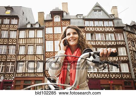 Stock Photography - Caucasian woman riding bicycle and talking on cell phone. Fotosearch