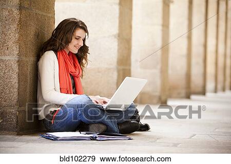 Stock Photo - Caucasian woman sitting on ground with laptop. Fotosearch