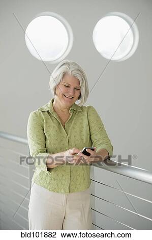 Stock Image - Caucasian woman text messaging on cell phone. Fotosearch
