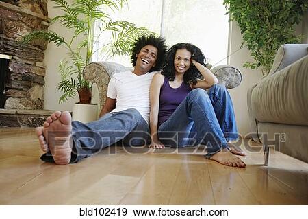 Stock Photo - Couple sitting on floor in living room. Fotosearch