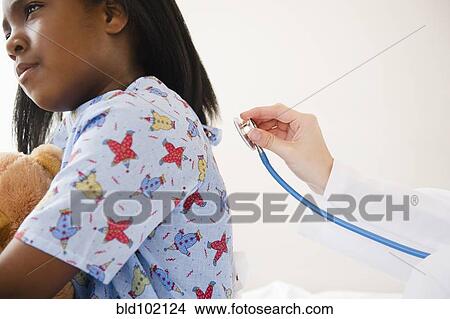 Picture - Doctor using stethoscope on Black girl in hospital. Fotosearch