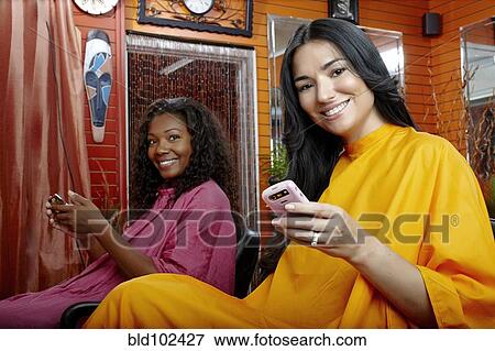 Stock Photo - Friends with cell phones in beauty salon. Fotosearch