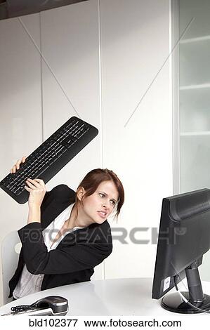 Stock Photo - Frustrated businesswoman about to hit computer with keyboard. Fotosearch