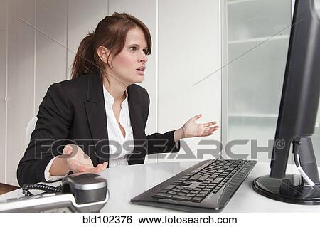 Stock Photograph - Frustrated businesswoman looking at computer. Fotosearch