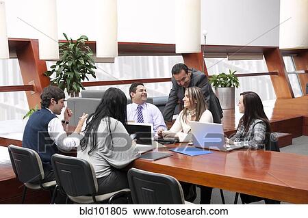 Stock Photography - Hispanic business people having meeting in conference room. Fotosearch
