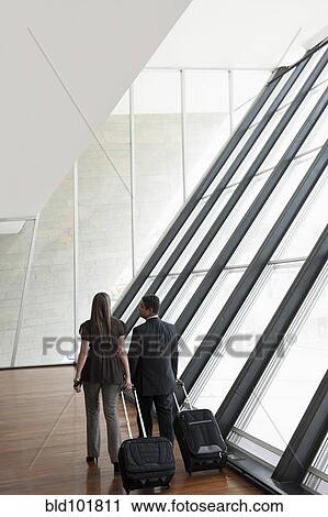 Stock Image - Hispanic business people pulling luggage. Fotosearch