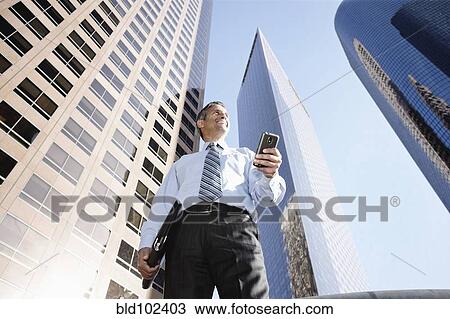 Hispanic businessman holding notebook and cell phone outdoors View Large Photo Image Stock Image - Hispanic businessman holding notebook and cell phone outdoors. Fotosearch