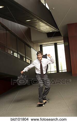 Hispanic businessman riding on skateboard View Large Photo Image Picture - Hispanic businessman riding on skateboard. Fotosearch