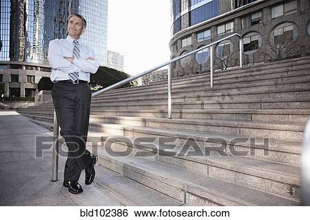 Stock Photograph - Hispanic businessman standing outdoors with arms crossed. Fotosearch
