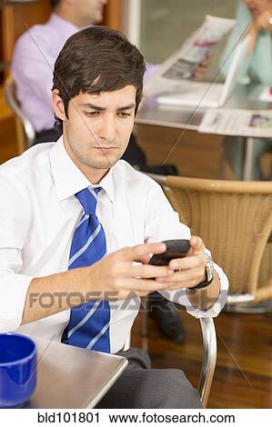 Stock Image - Hispanic businessman text messaging on cell phone. Fotosearch