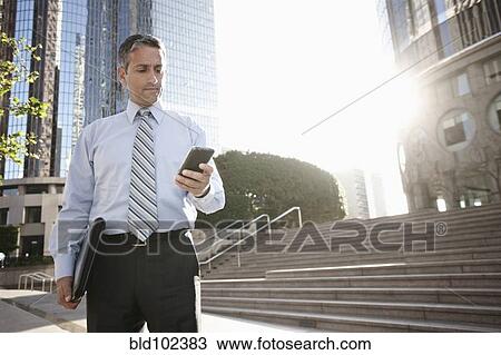 Hispanic businessman text messaging on cell phone outdoors View Large Photo Image Stock Image - Hispanic businessman text messaging on cell phone outdoors. Fotosearch