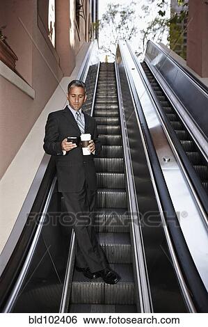 Hispanic businessman text messaging on escalator View Large Photo Image Stock Photograph - Hispanic businessman text messaging on escalator. Fotosearch