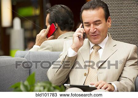 Hispanic businessman using cell phone and digital tablet View Large Photo Image Stock Image - Hispanic businessman using cell phone and digital tablet. Fotosearch