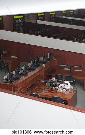 Stock Photograph - Hispanic businessmen having meeting in library. Fotosearch