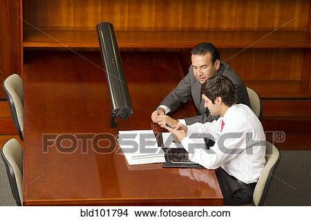 Picture - Hispanic businessmen working in conference room. Fotosearch