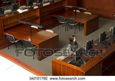 Stock Image - Hispanic businesswoman working in library. Fotosearch