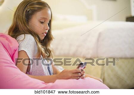 Hispanic girl text messaging on cell phone in bedroom View Large Photo Image Stock Photo - Hispanic girl text messaging on cell phone in bedroom. Fotosearch