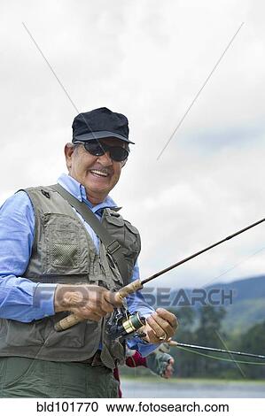 Stock Image - Hispanic man fishing in lake. Fotosearch