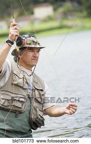 Stock Image - Hispanic man fishing in lake. Fotosearch