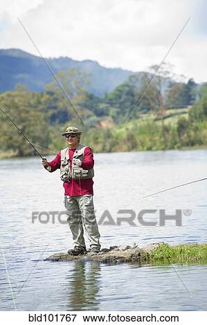 Stock Photo - Hispanic man fishing in lake. Fotosearch