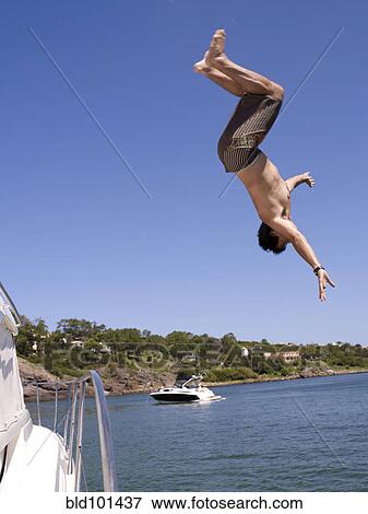Stock Photo - Hispanic man jumping from sailboat. Fotosearch