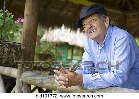 Stock Image - Hispanic man leaning on railing. Fotosearch