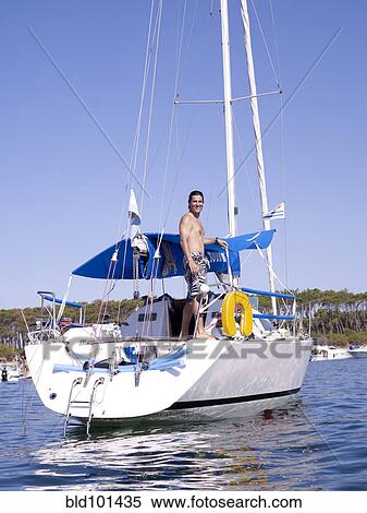Stock Photography - Hispanic man standing on sailboat. Fotosearch