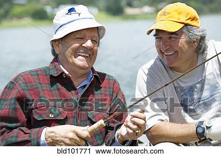 Stock Image - Hispanic men fishing in lake. Fotosearch