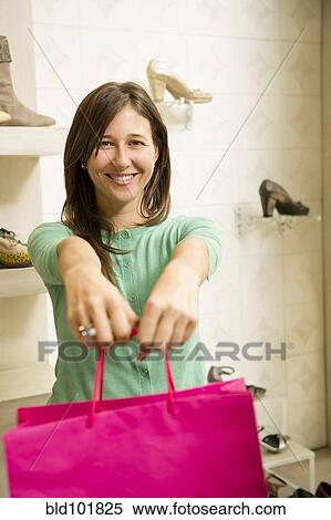 Stock Photography - Hispanic woman holding bag in shoe store. Fotosearch
