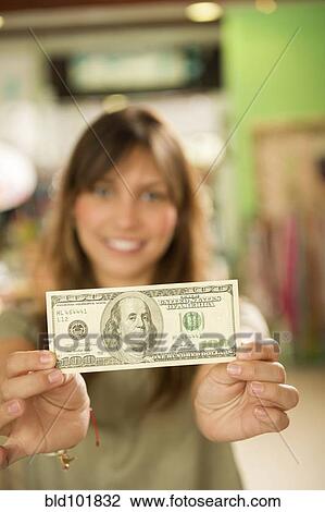 Stock Image - Hispanic woman holding cash in store. Fotosearch