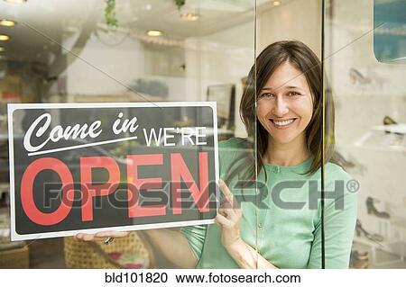 Hispanic woman holding open sign in shoe store View Large Photo Image Stock Image - Hispanic woman holding open sign in shoe store. Fotosearch