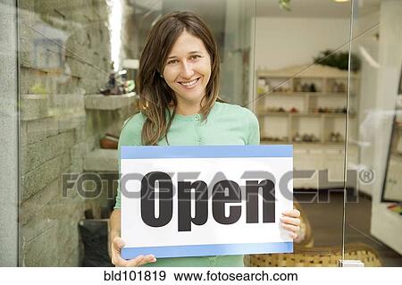 Hispanic woman holding open sign in shoe store View Large Photo Image Stock Photo - Hispanic woman holding open sign in shoe store. Fotosearch