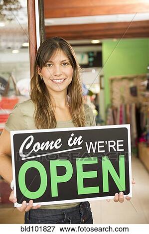 Hispanic woman holding open sign in store View Large Photo Image Stock Photo - Hispanic woman holding open sign in store. Fotosearch
