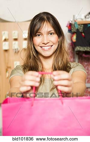 Hispanic woman holding out bag in store View Large Photo Image Stock Photograph - Hispanic woman holding out bag in store. Fotosearch
