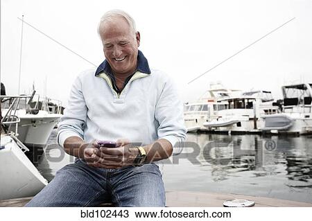 Man using cell phone in marina View Large Photo Image Stock Image - Man using cell phone in marina. Fotosearch
