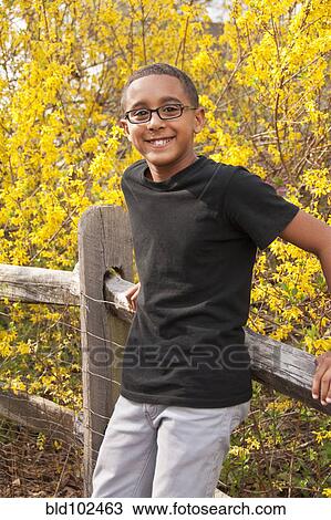 Mixed race boy leaning on fence View Large Photo Image Stock Image - Mixed race boy leaning on fence. Fotosearch