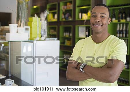 Stock Image - Mixed race business owner standing in shop. Fotosearch