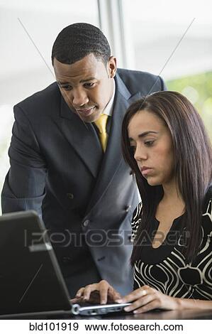 Stock Photo - Mixed race business people looking at laptop. Fotosearch