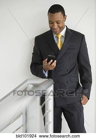 Picture - Mixed race businessman looking at cell phone. Fotosearch
