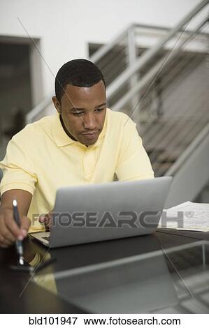 Stock Photo - Mixed race businessman using laptop. Fotosearch