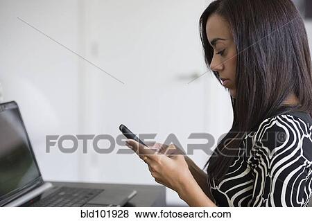 Stock Photo - Mixed race businesswoman text messaging on cell phone. Fotosearch