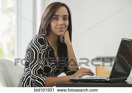 Stock Image - Mixed race businesswoman typing on laptop. Fotosearch