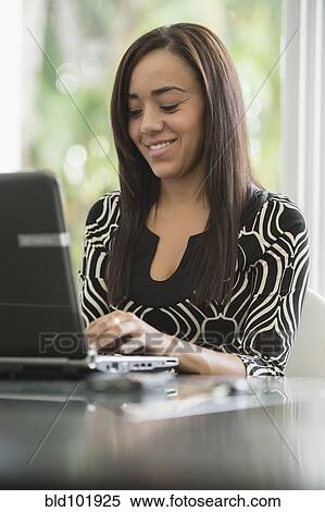 Stock Photography - Mixed race businesswoman typing on laptop. Fotosearch