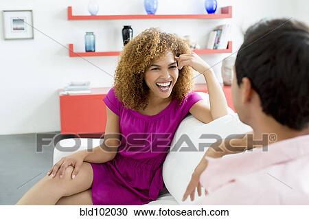 Mixed race couple sitting on sofa talking View Large Photo Image Stock Image - Mixed race couple sitting on sofa talking. Fotosearch