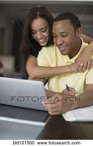 Stock Image - Mixed race couple using laptop. Fotosearch