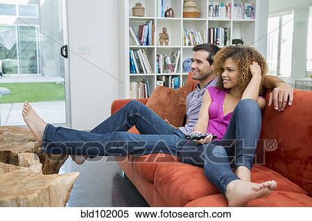 Stock Photography - Mixed race couple watching television together. Fotosearch