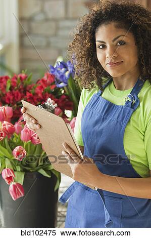 Stock Photography - Mixed race florist holding clipboard. Fotosearch