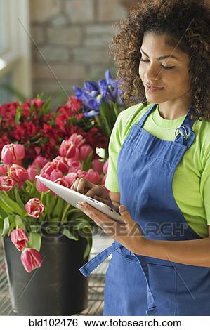Stock Photograph - Mixed race florist using digital tablet. Fotosearch