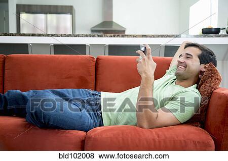 Stock Photo - Mixed race man text messaging on cell phone. Fotosearch
